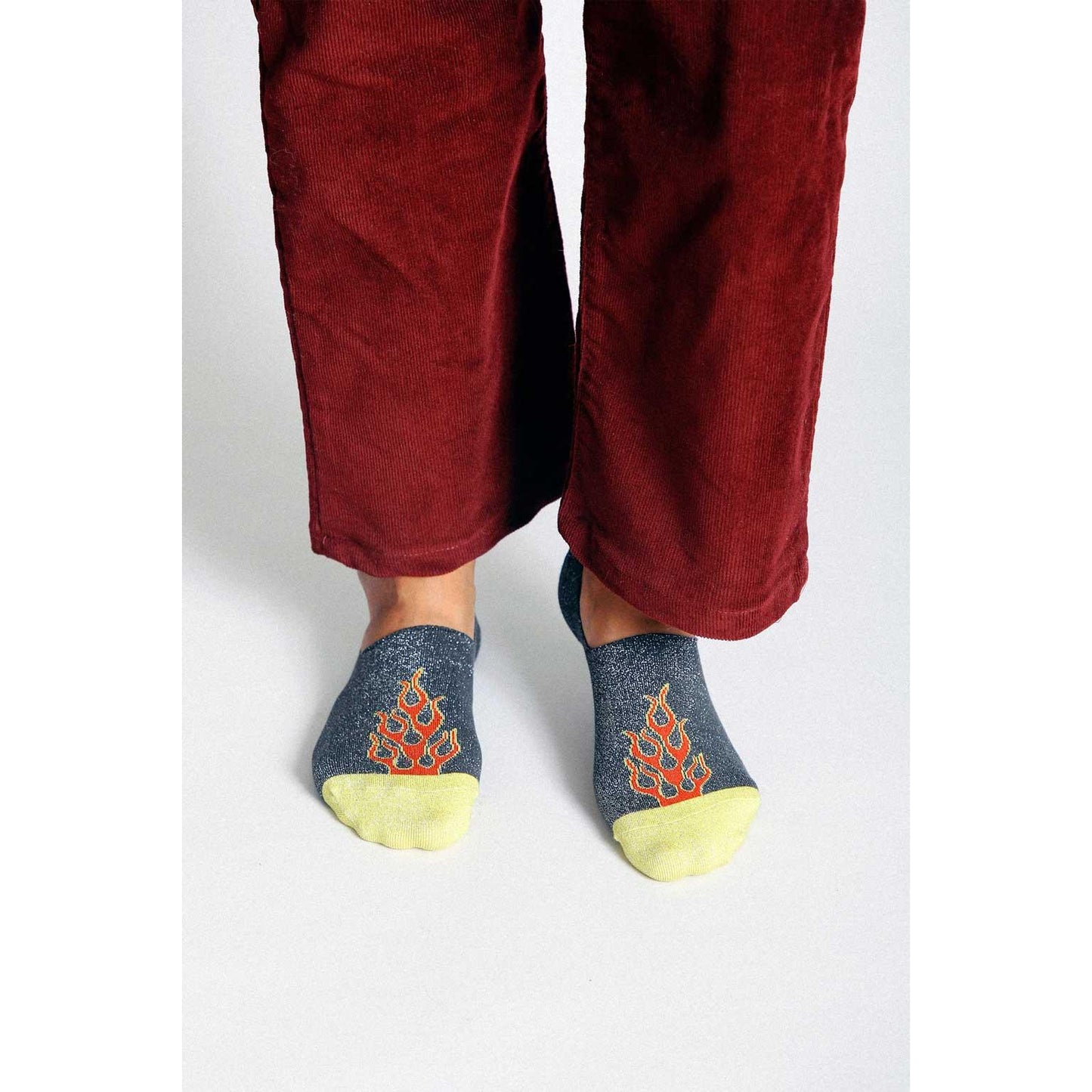 Person wearing maroon pants and no-show socks with flame design