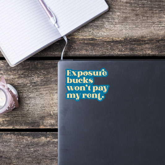 Black notebook with a blue sticker on a wooden surface with a notebook and pen.