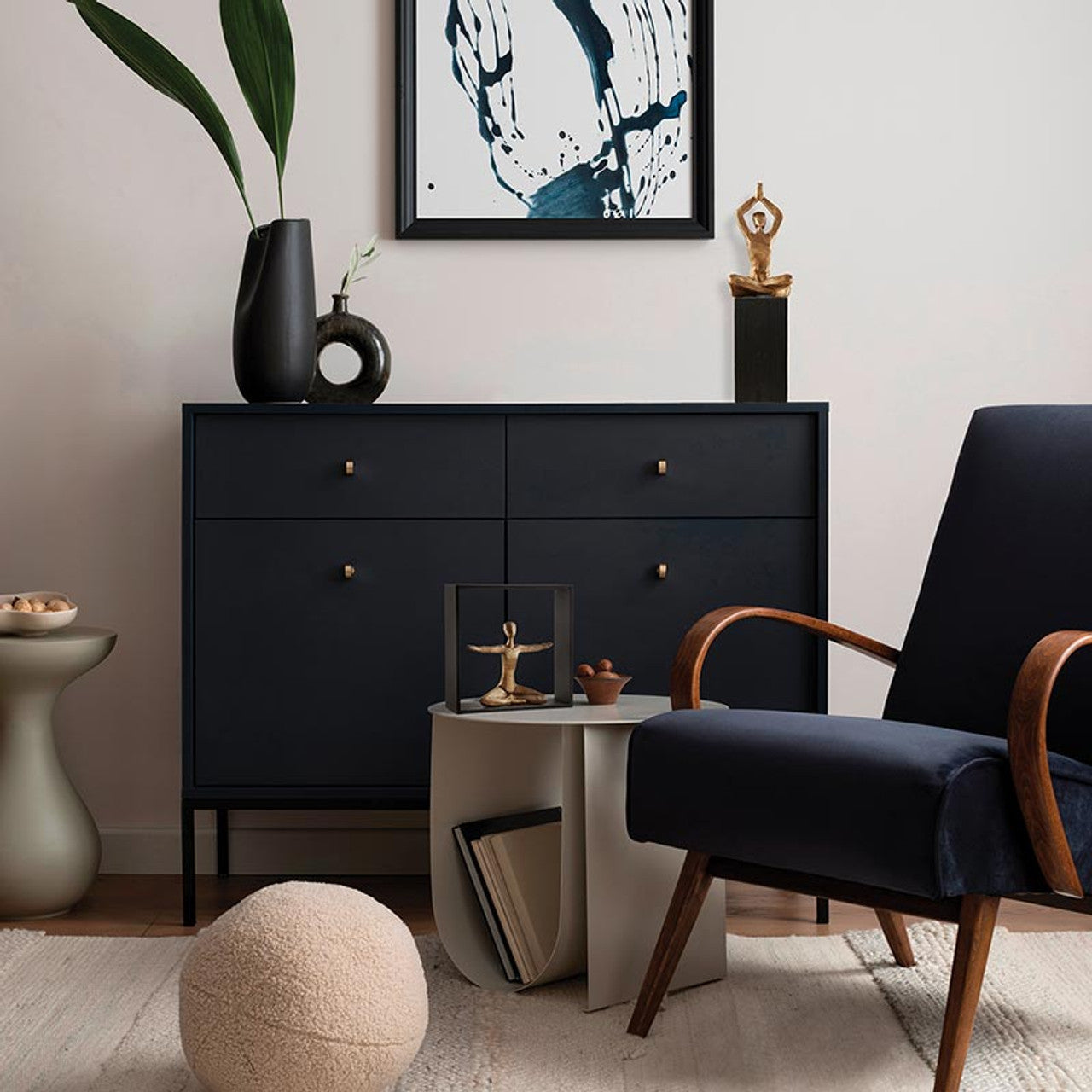 Modern interior with a black dresser, navy chair, and abstract art on a light wall.