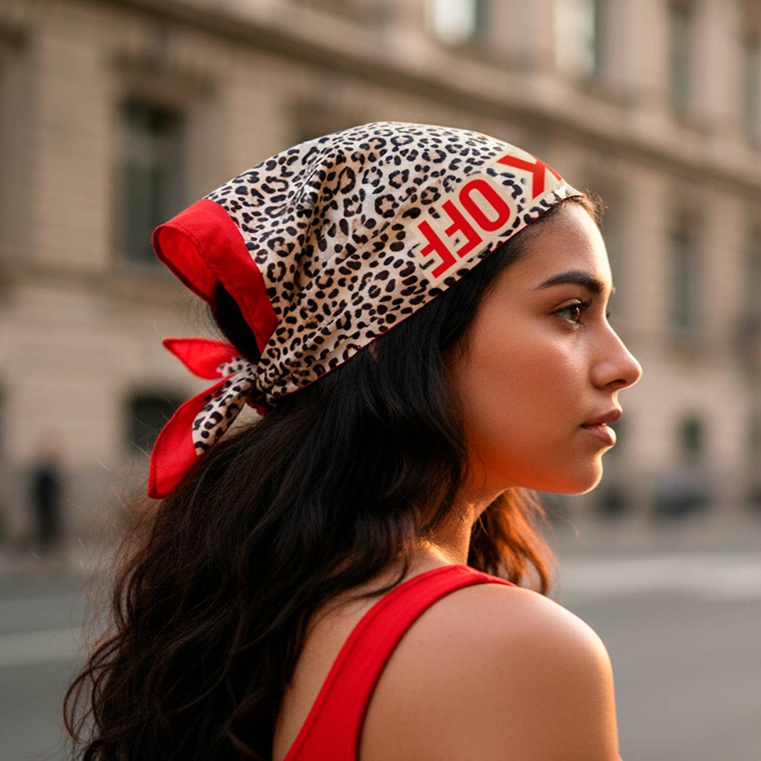Woman wearing a leopard print headscarf with red accents in an urban setting