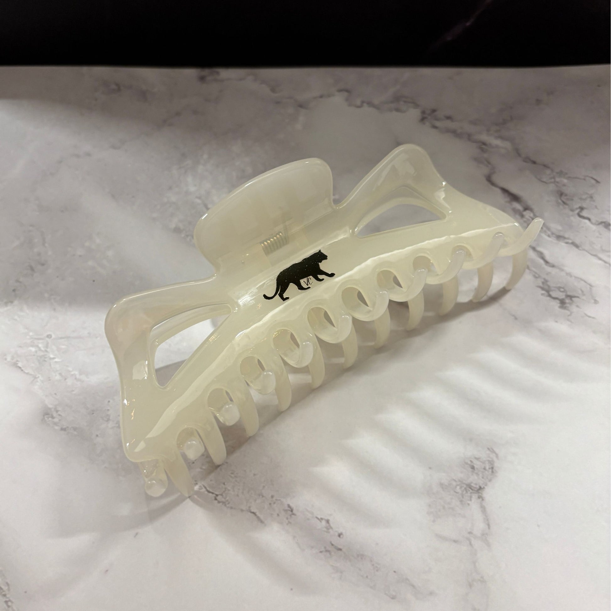 White hair clip with gold panther design on a marble surface
