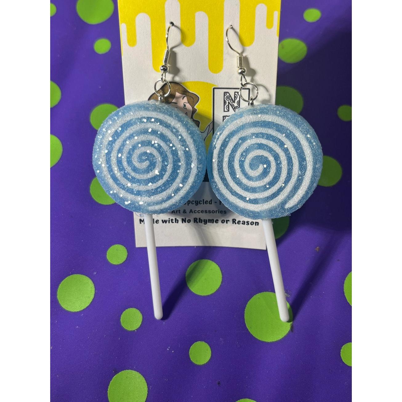 Blue spiral lollipop earrings on a purple and green polka dot background
