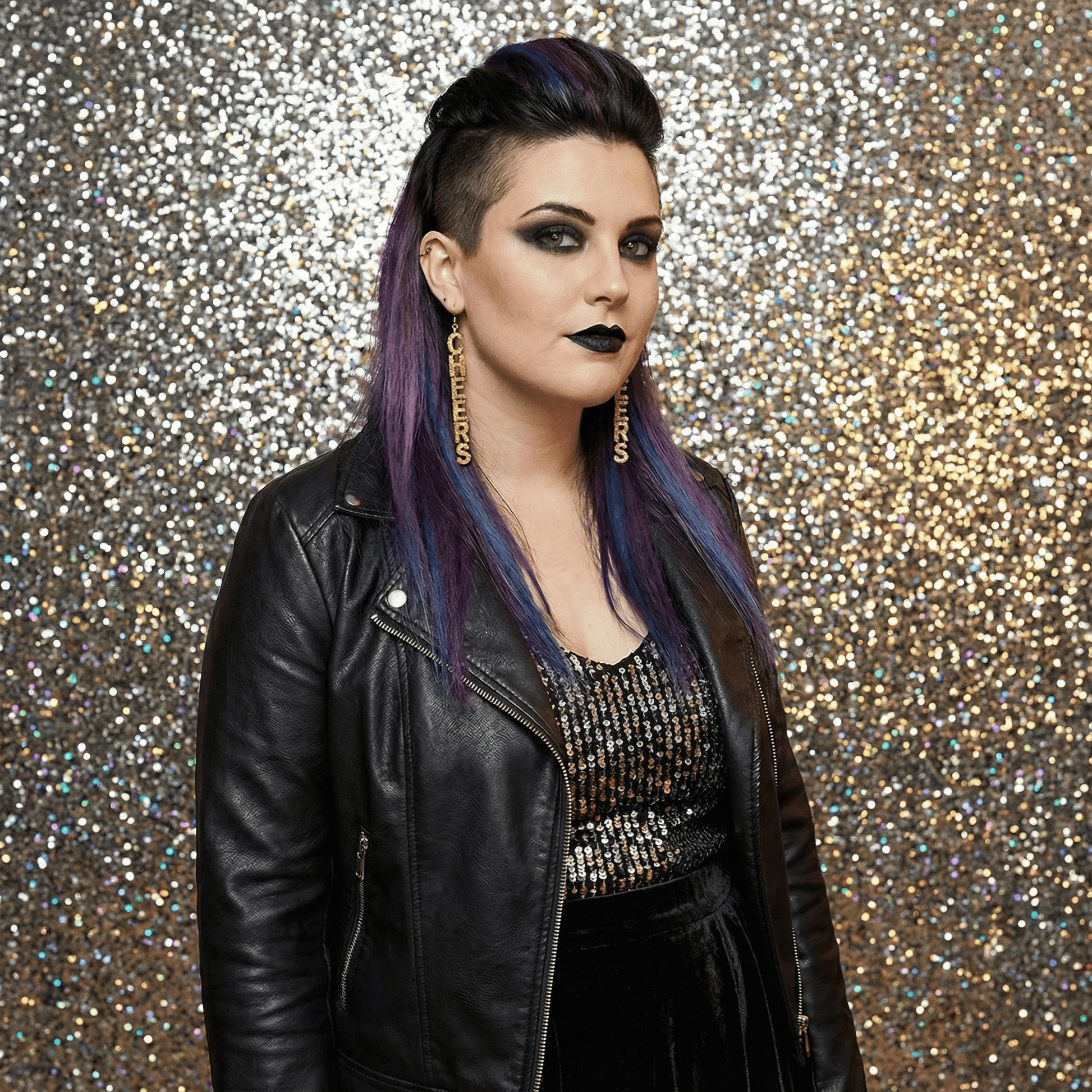 Person with purple hair and black leather jacket against a glittery background