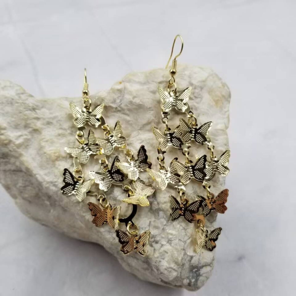 Butterfly-shaped earrings on a rock with a white background