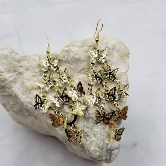 Butterfly-shaped earrings on a rock with a white background