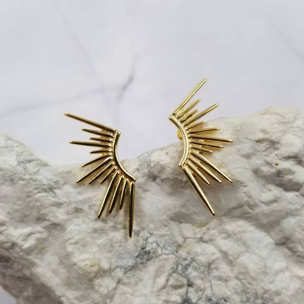 Gold sunburst earrings on a marble surface