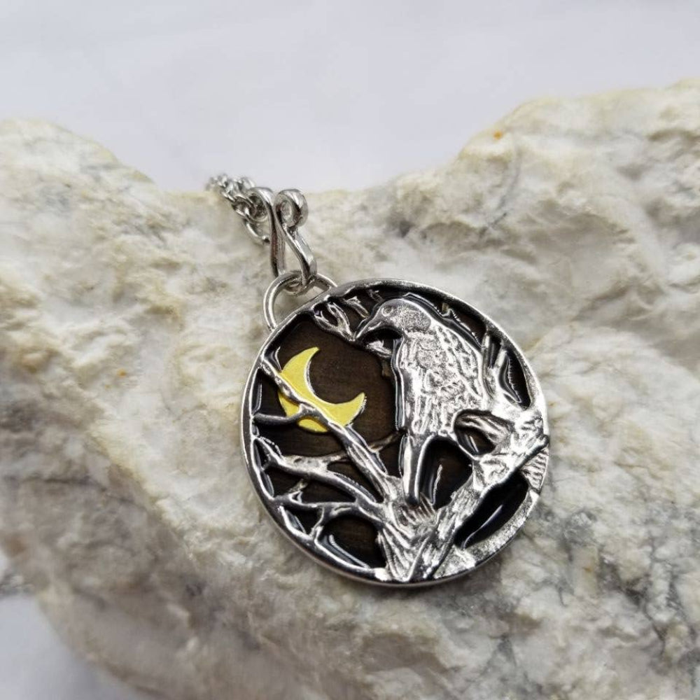 Silver pendant with a bird design on a rock