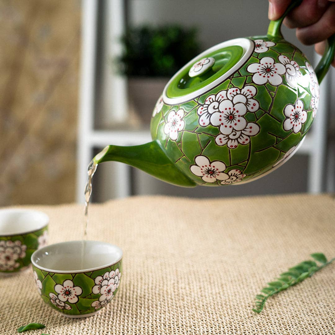 Green floral teapot and cup being used to pour tea