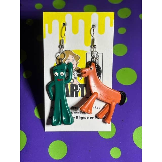 Colorful cartoon-style earrings on a display card with a purple and green polka dot background.