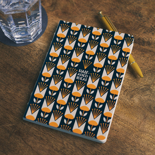 Notebook with a geometric pattern on a wooden surface with a glass and pen.