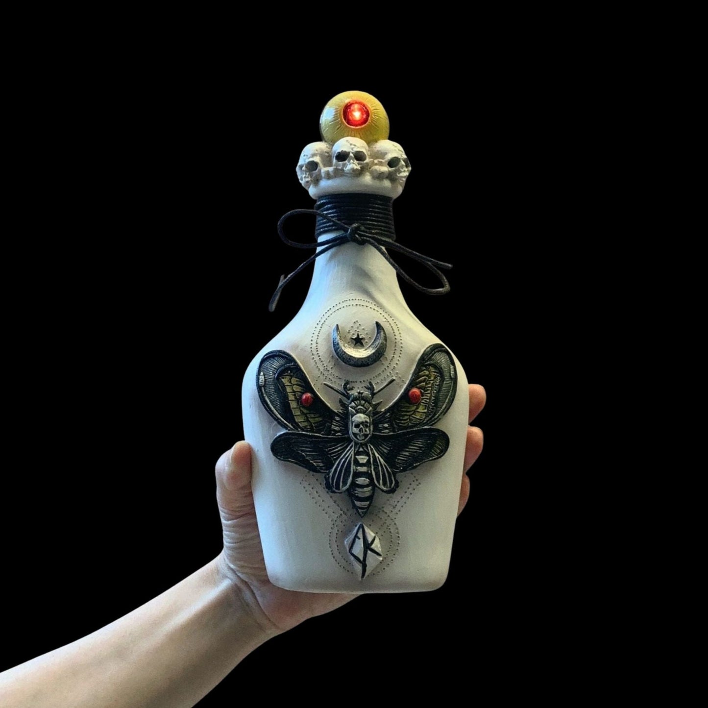 Decorative bottle held by a hand against a black background