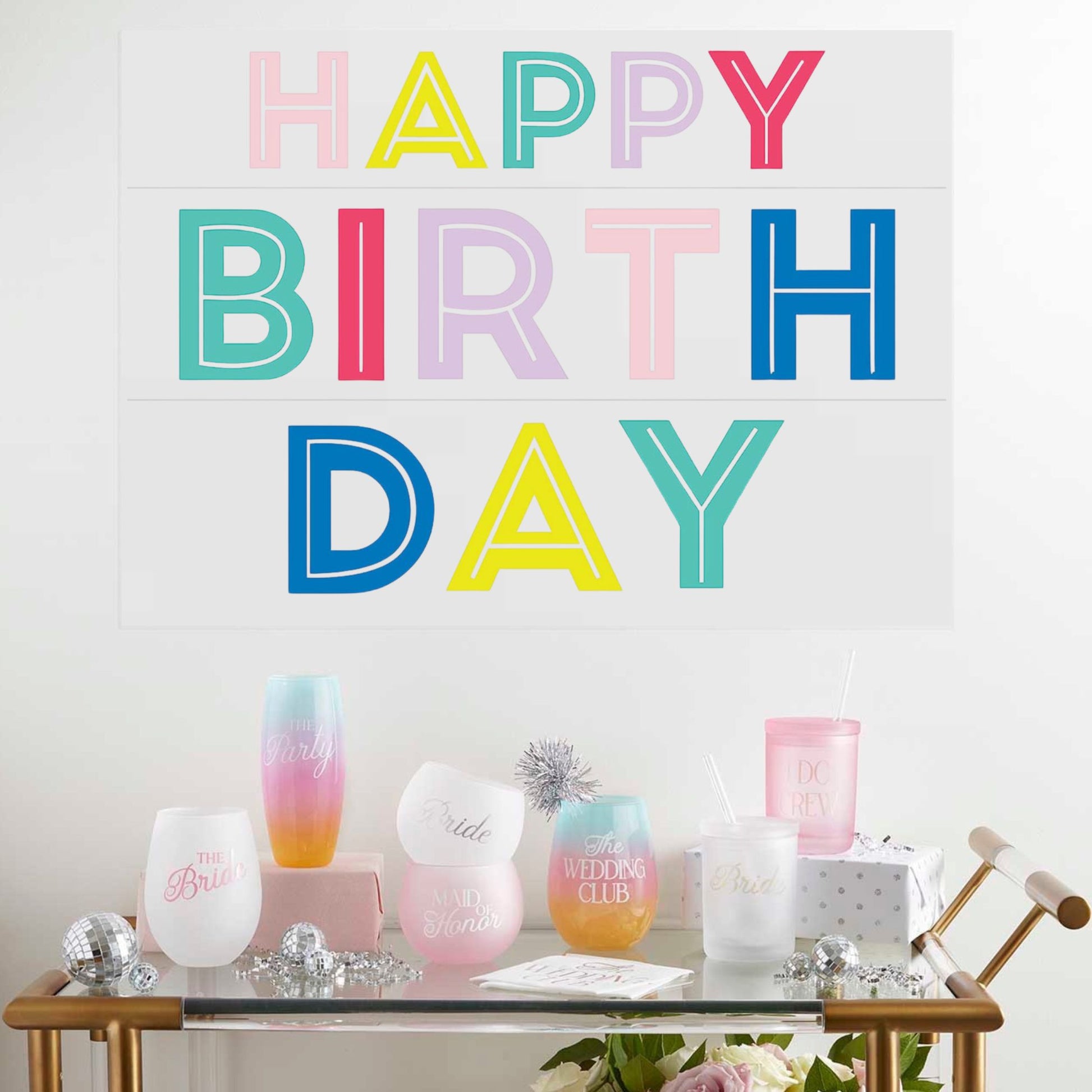 Decorative setup with 'Happy Birthday' sign and pastel-colored items on a table.