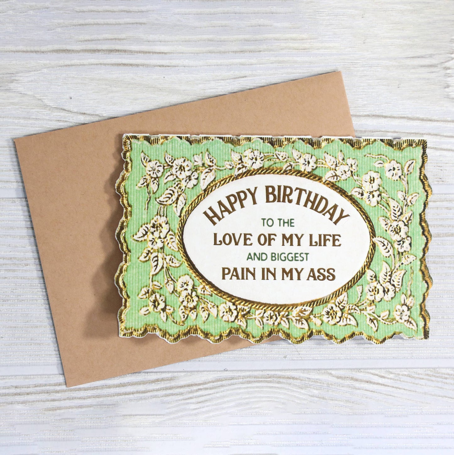 Birthday card with decorative border and humorous message on a wooden surface