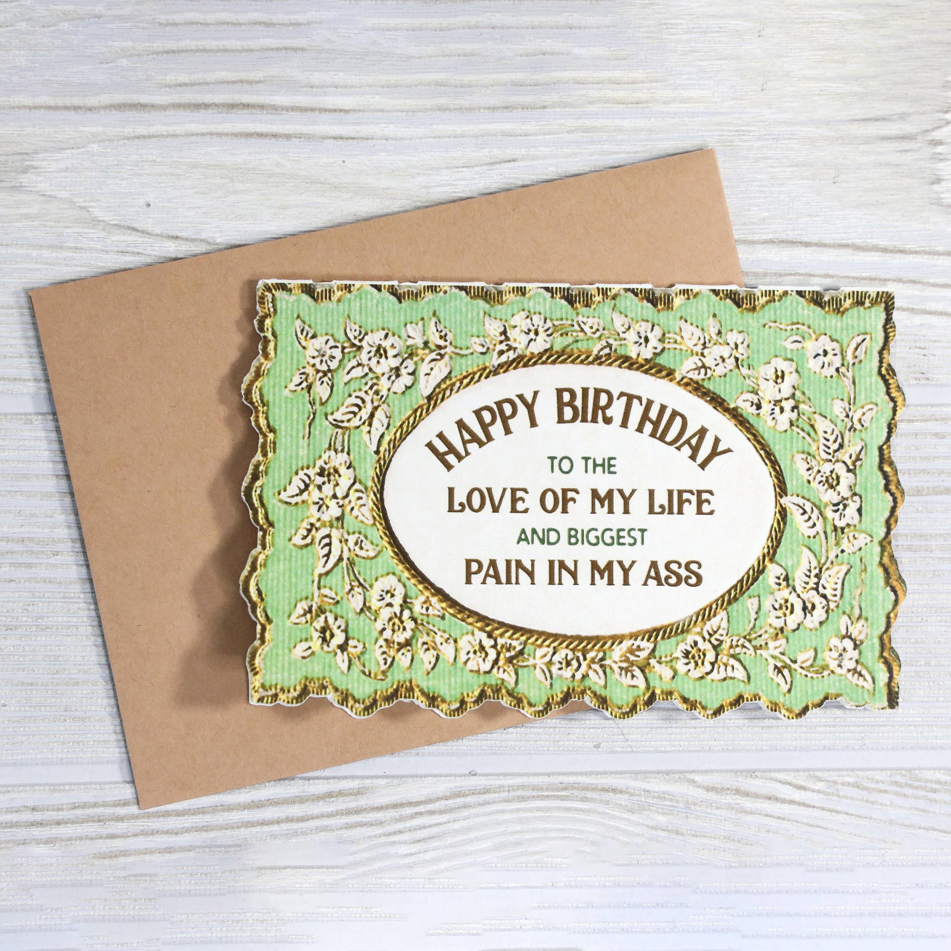 Birthday card with decorative border and humorous message on a wooden surface