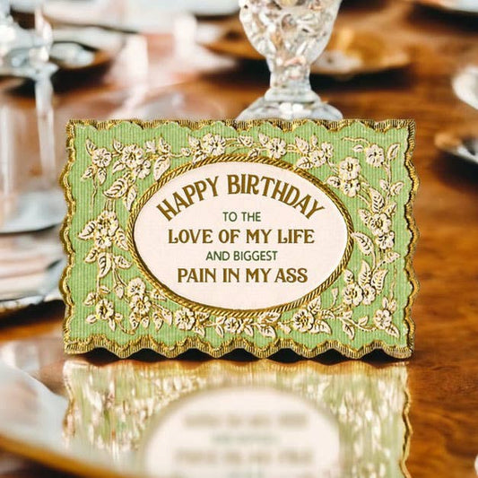 Vintage-style birthday card with humorous message on a wooden surface