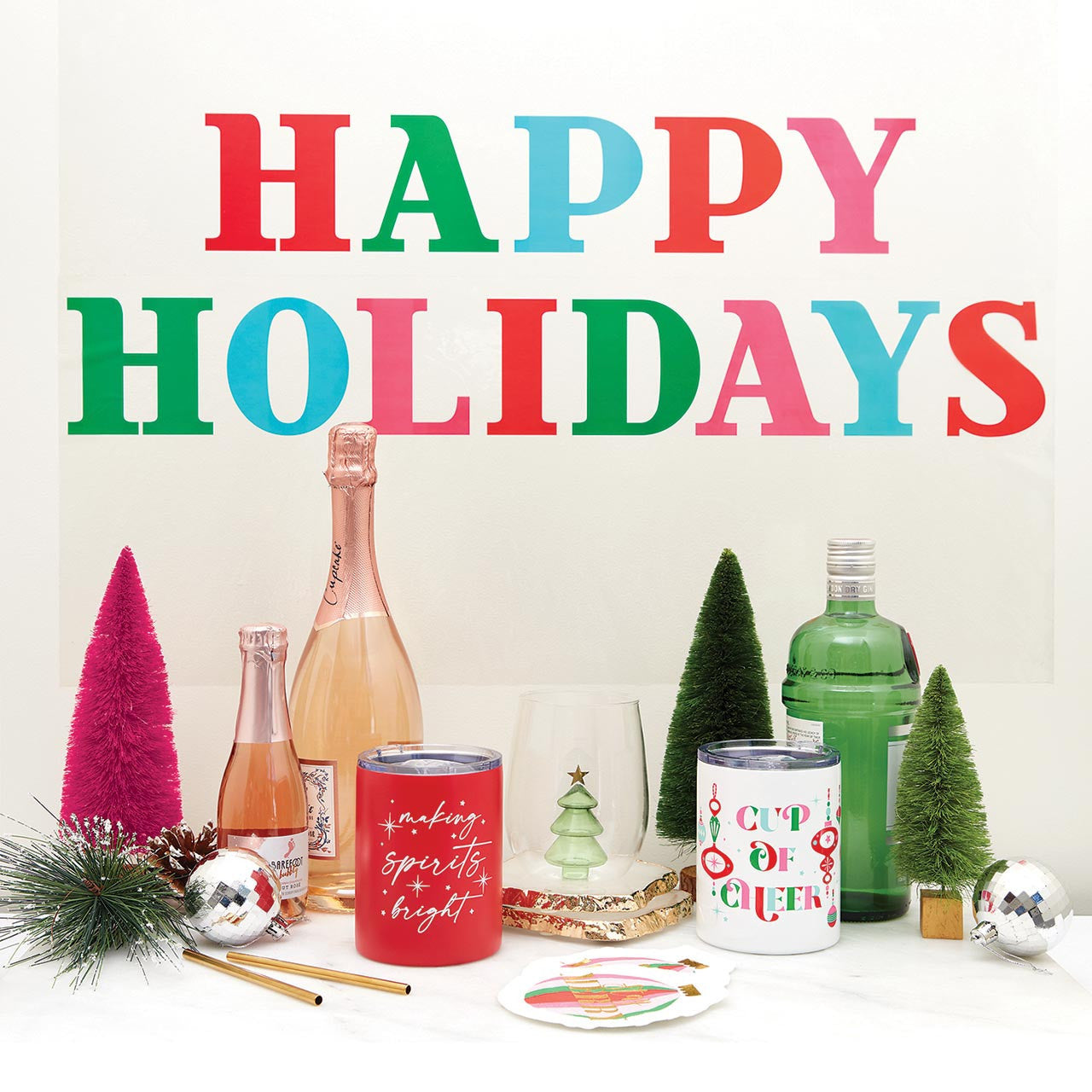 Decorative setup with 'Happy Holidays' text, bottles, and festive items on a white background