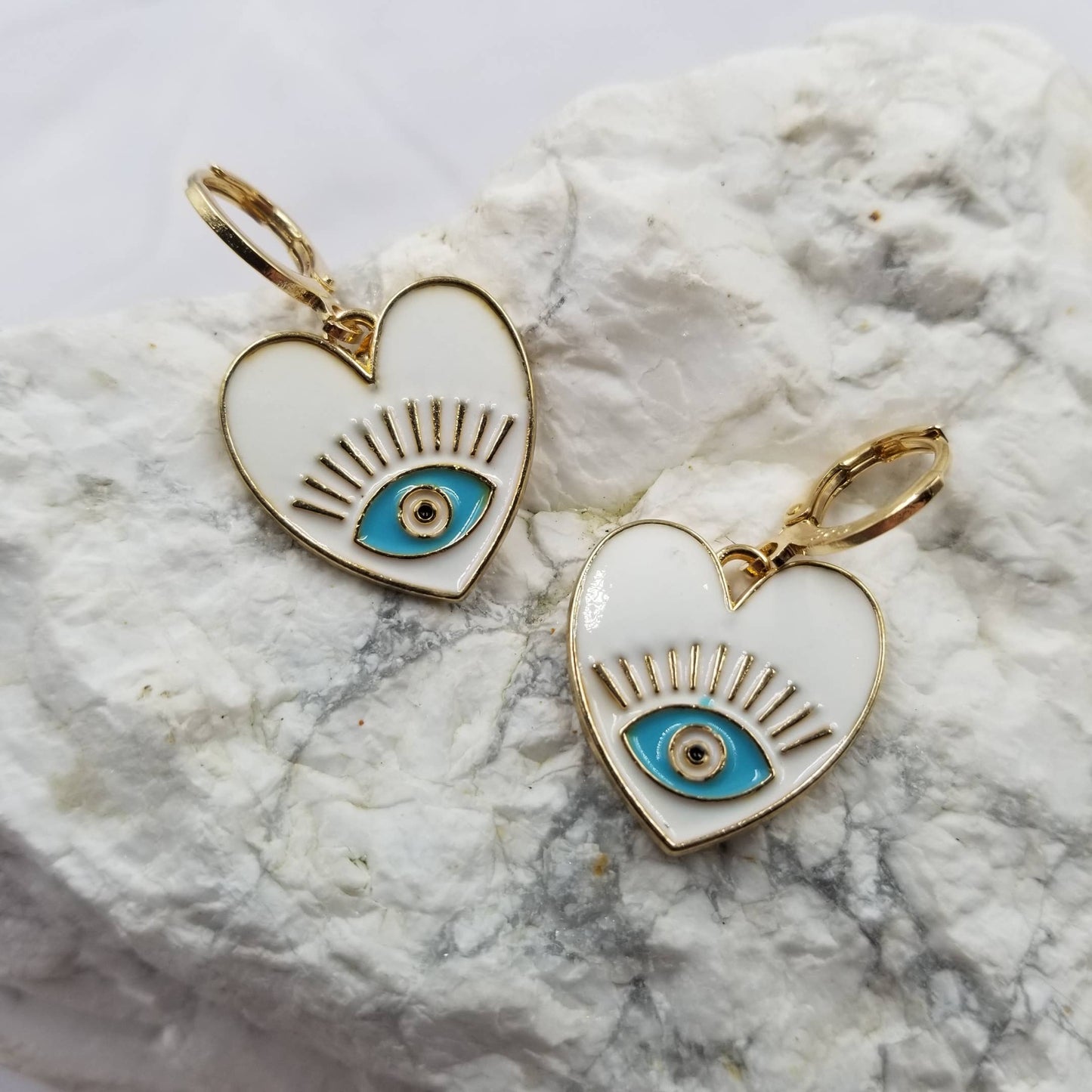 White heart-shaped eye pendants on a marble surface