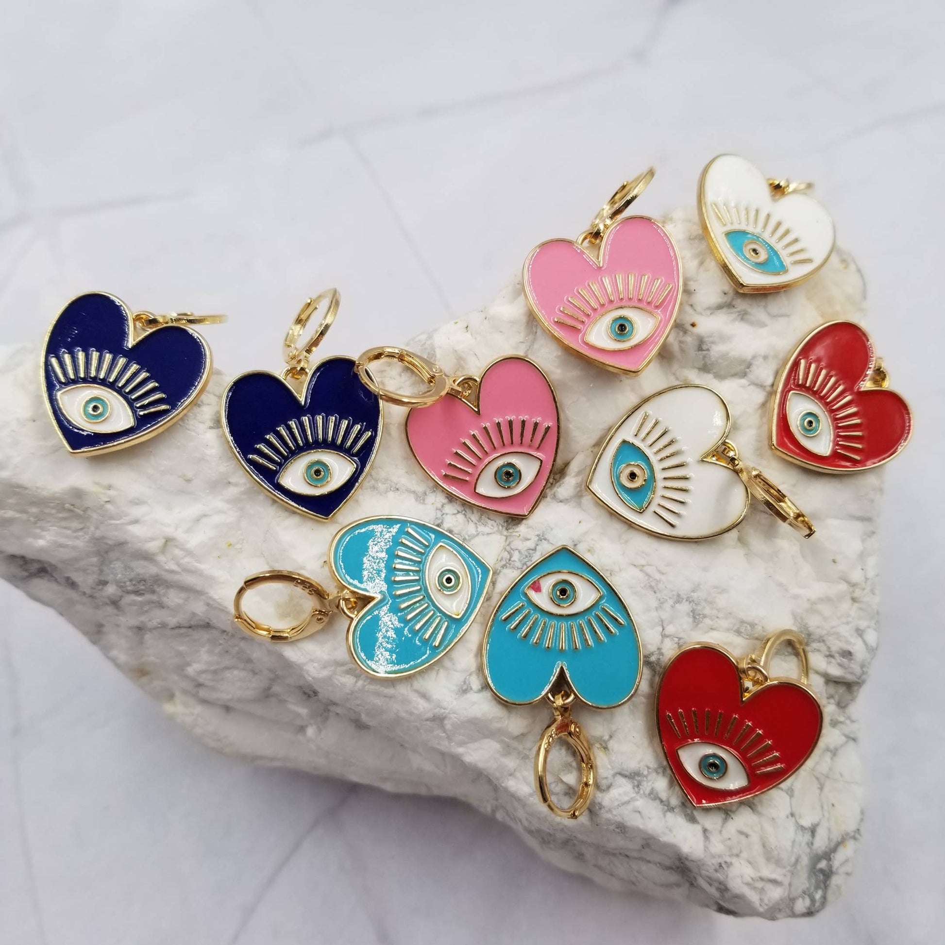 Colorful heart-shaped eye earrings on a stone surface