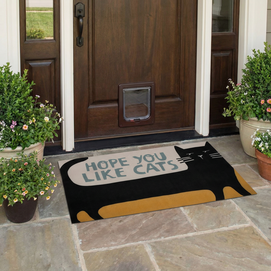 Doormat with cat design and text 'Hope you like cats' in front of a wooden door.
