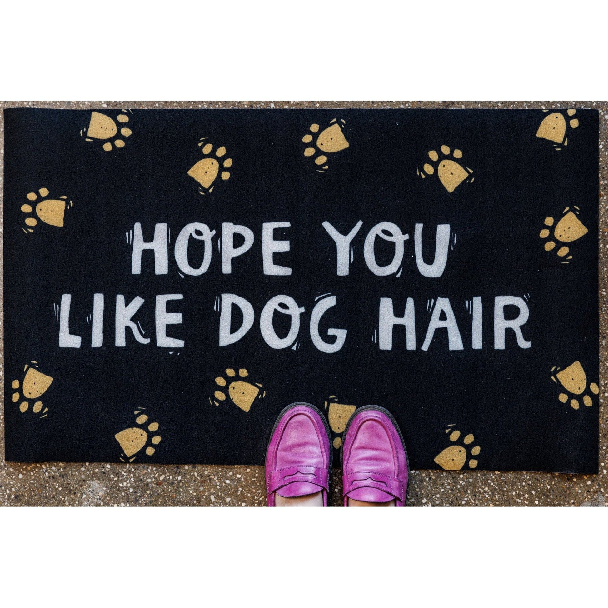 Doormat with 'Hope you like dog hair' text and paw prints, worn by pink shoes.