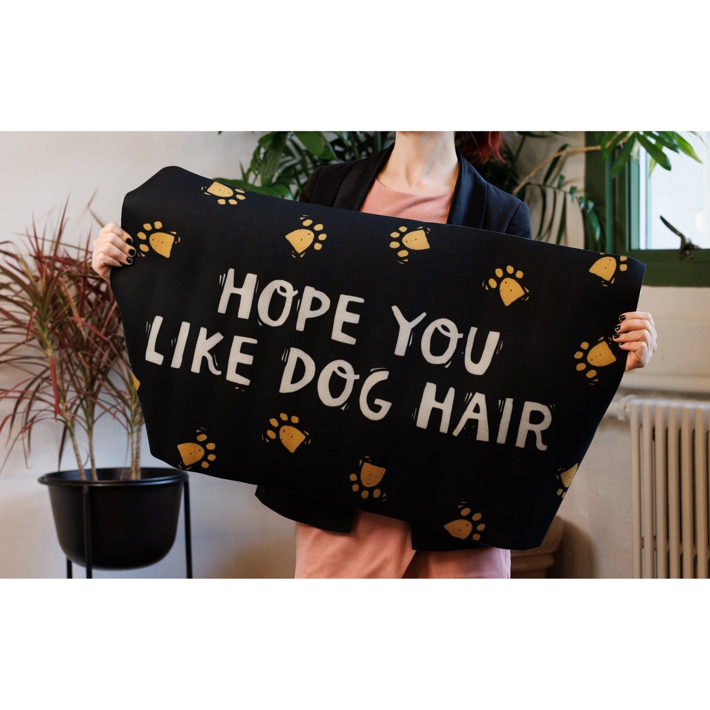 Person holding a black towel with 'Hope you like dog hair' text and paw prints.