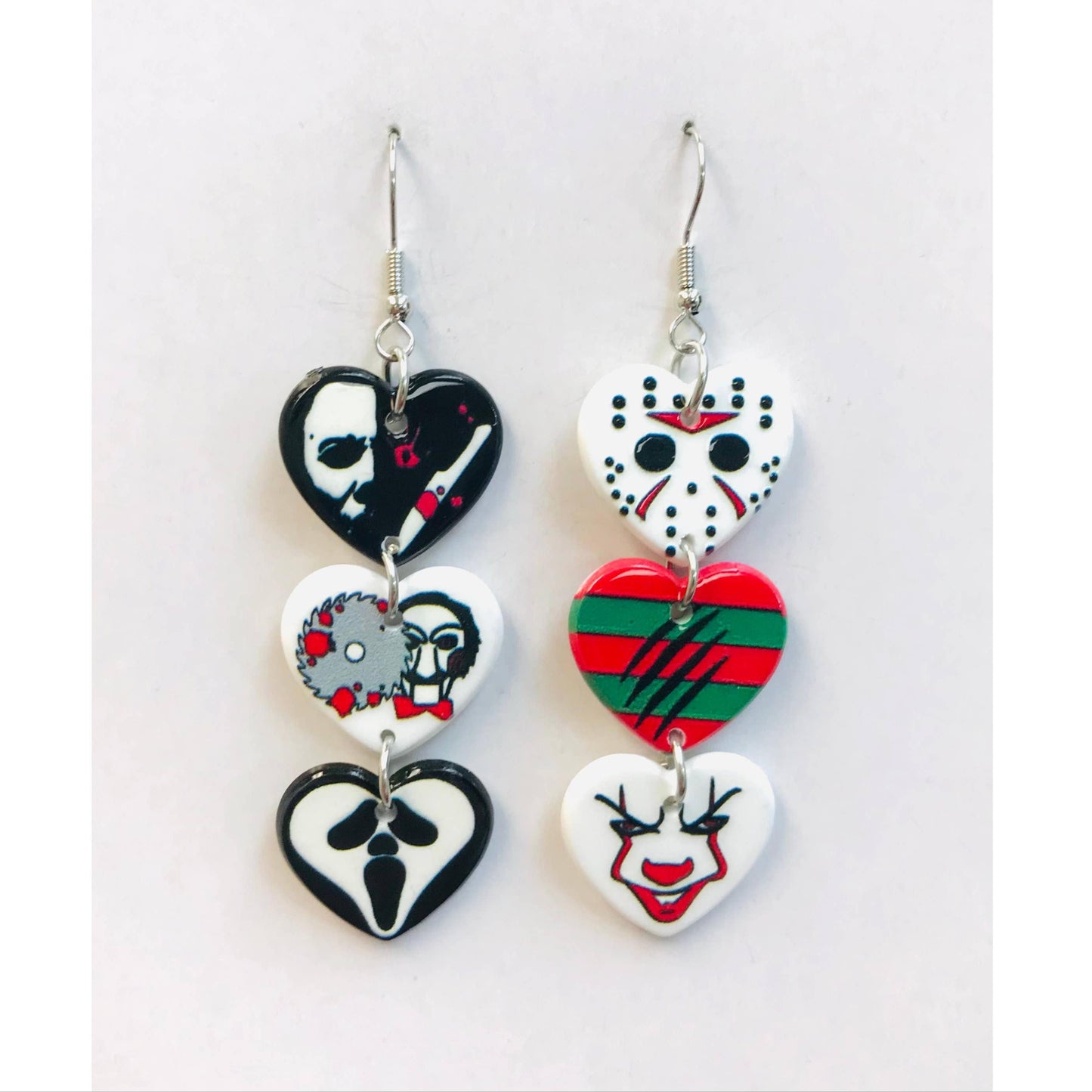 Pair of heart-shaped earrings with horror movie designs on a white background