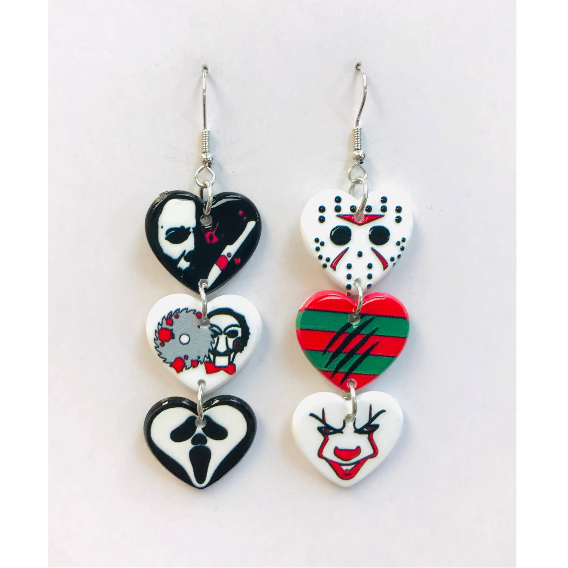 Pair of heart-shaped earrings with horror movie designs on a white background