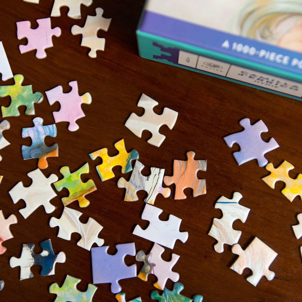 Jigsaw puzzle pieces on a wooden surface with a box in the background