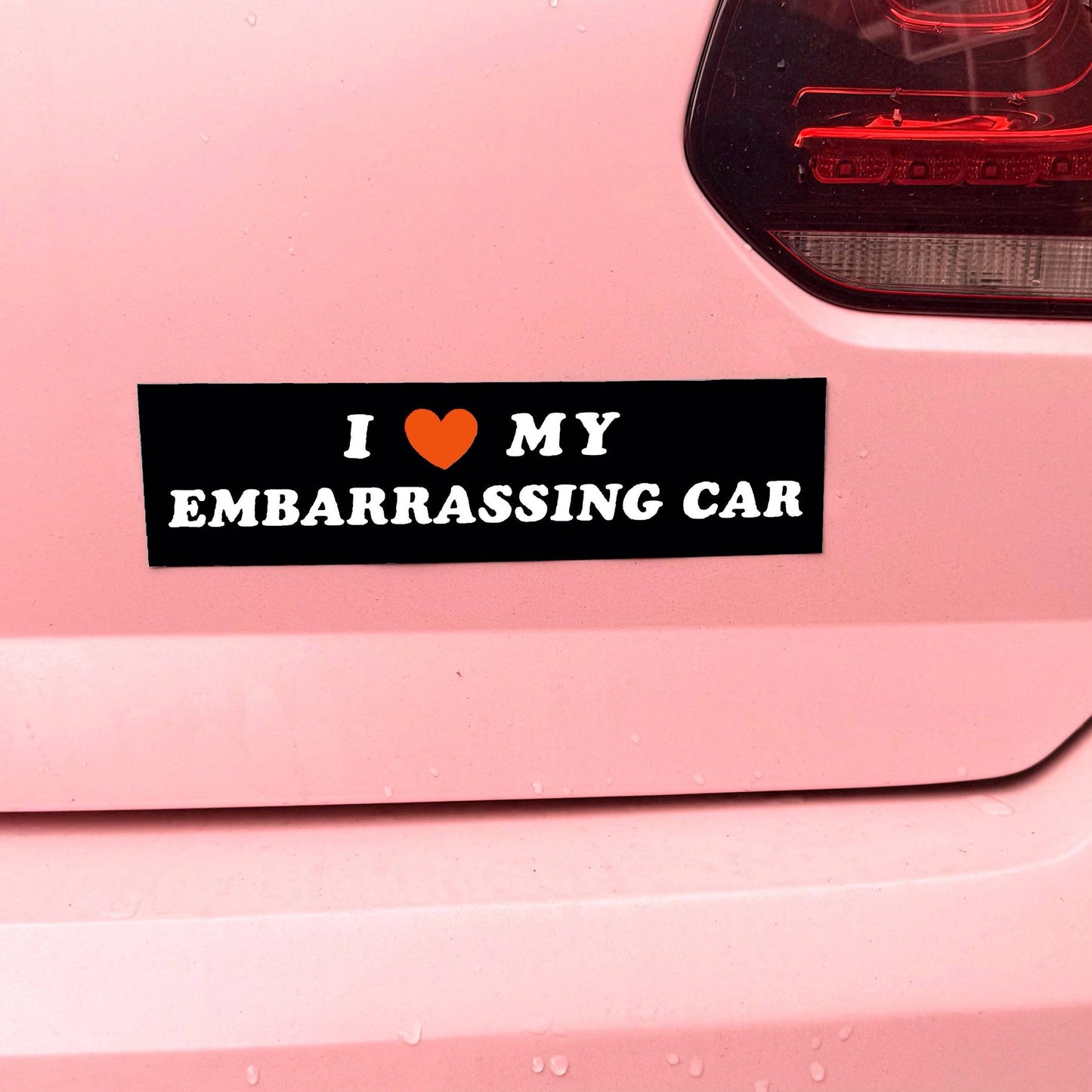 Sticker on a pink car reading 'I ❤️ MY EMBARRASSING CAR' with a red heart symbol.