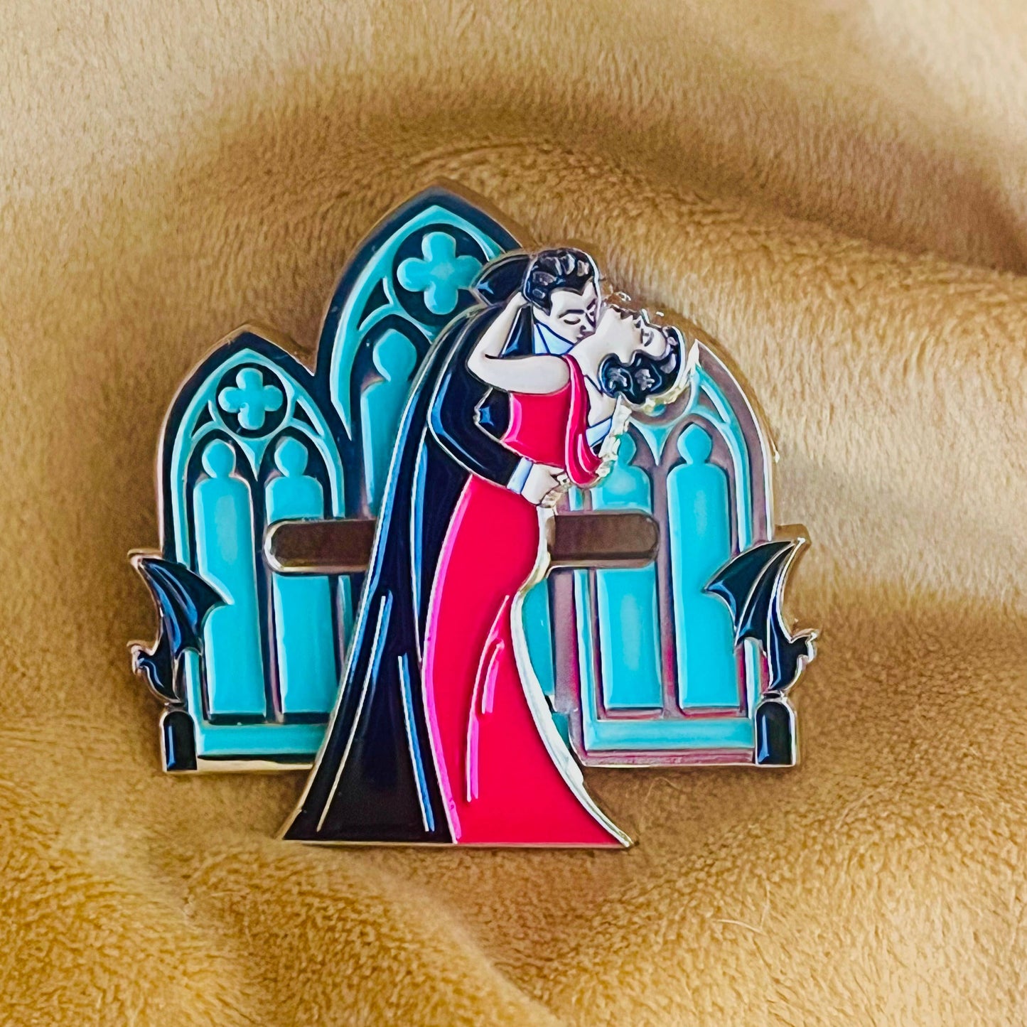 Enamel pin with a design of a woman in a red dress being lifted by a man, set against a blue archway