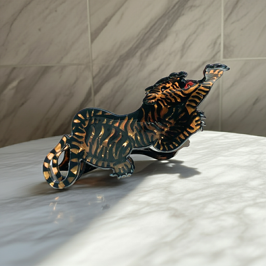 Metallic tiger figurine on a marble surface with a neutral background