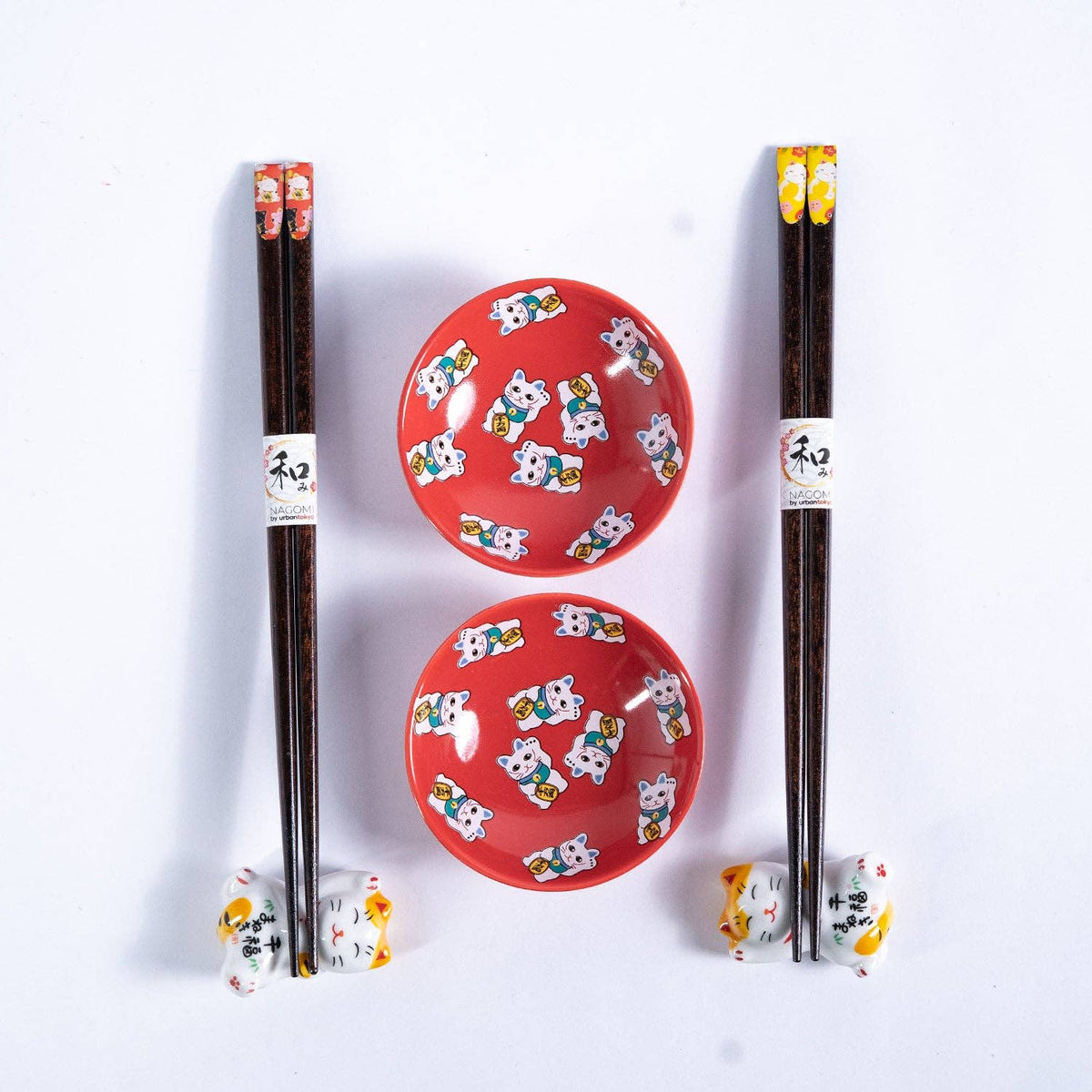Two red ceramic sauce dish with cat designs and chopsticks