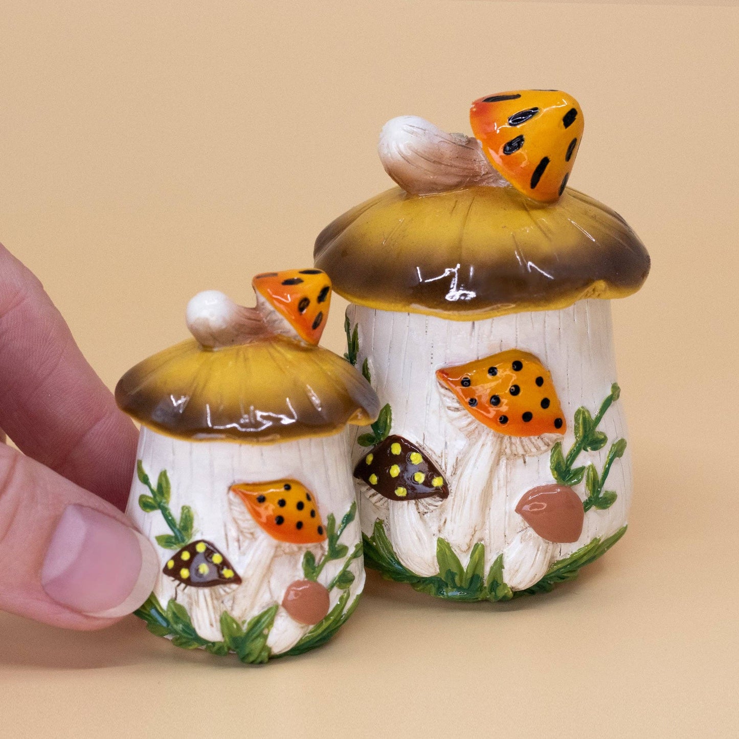 Two ceramic mushroom-shaped decorative painted mushrooms and green leaves