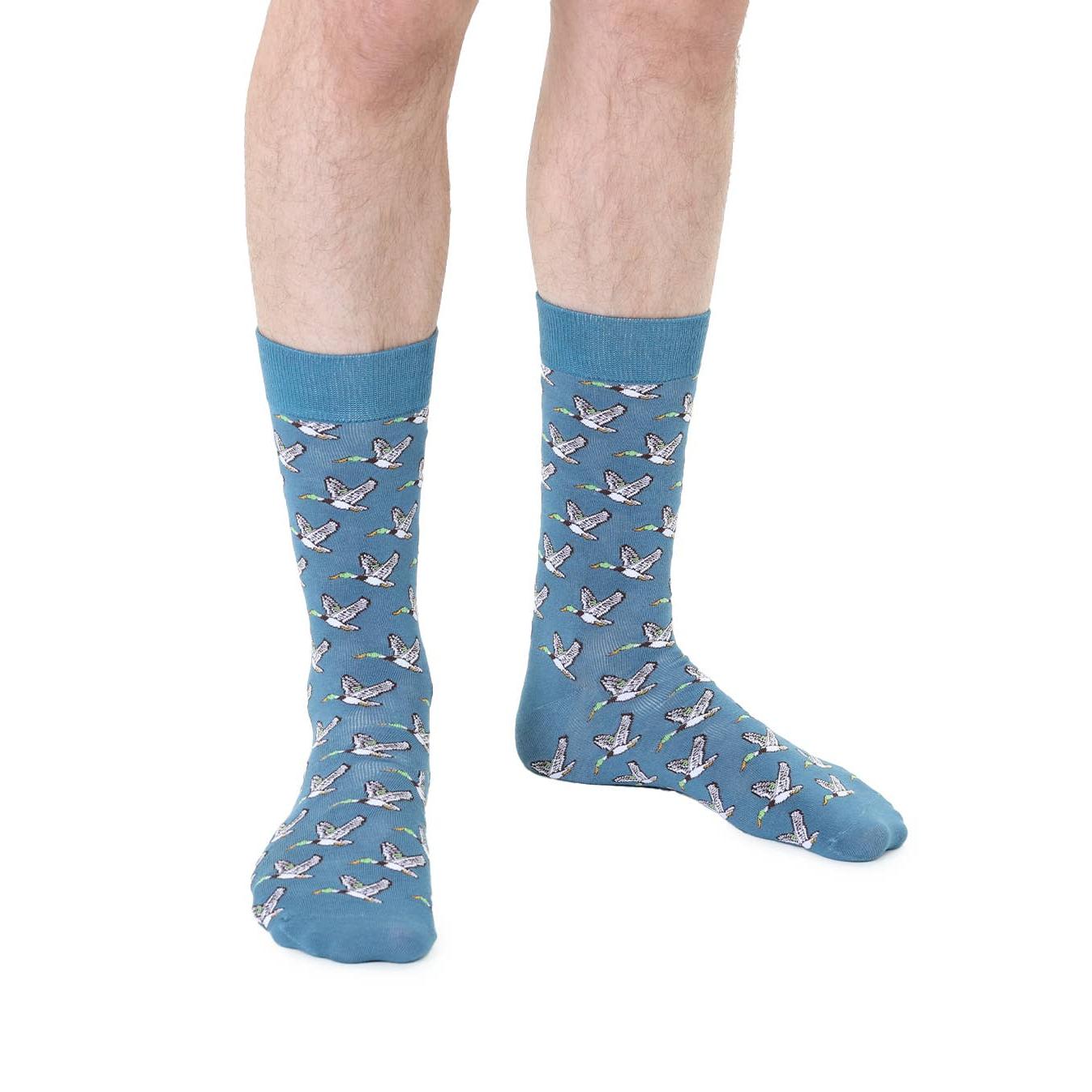 Blue socks with bird pattern worn by a person on a white background