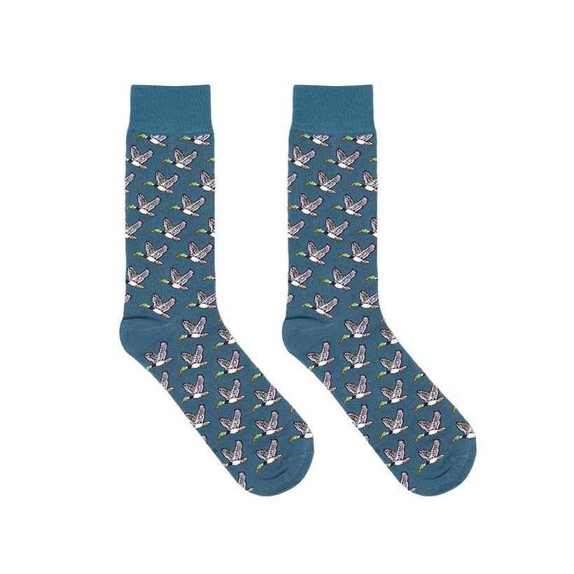 A pair of crew socks in a muted teal blue color, featuring an all-over repeating pattern of small white cranes with pink and yellow accents, displayed against a solid white background.