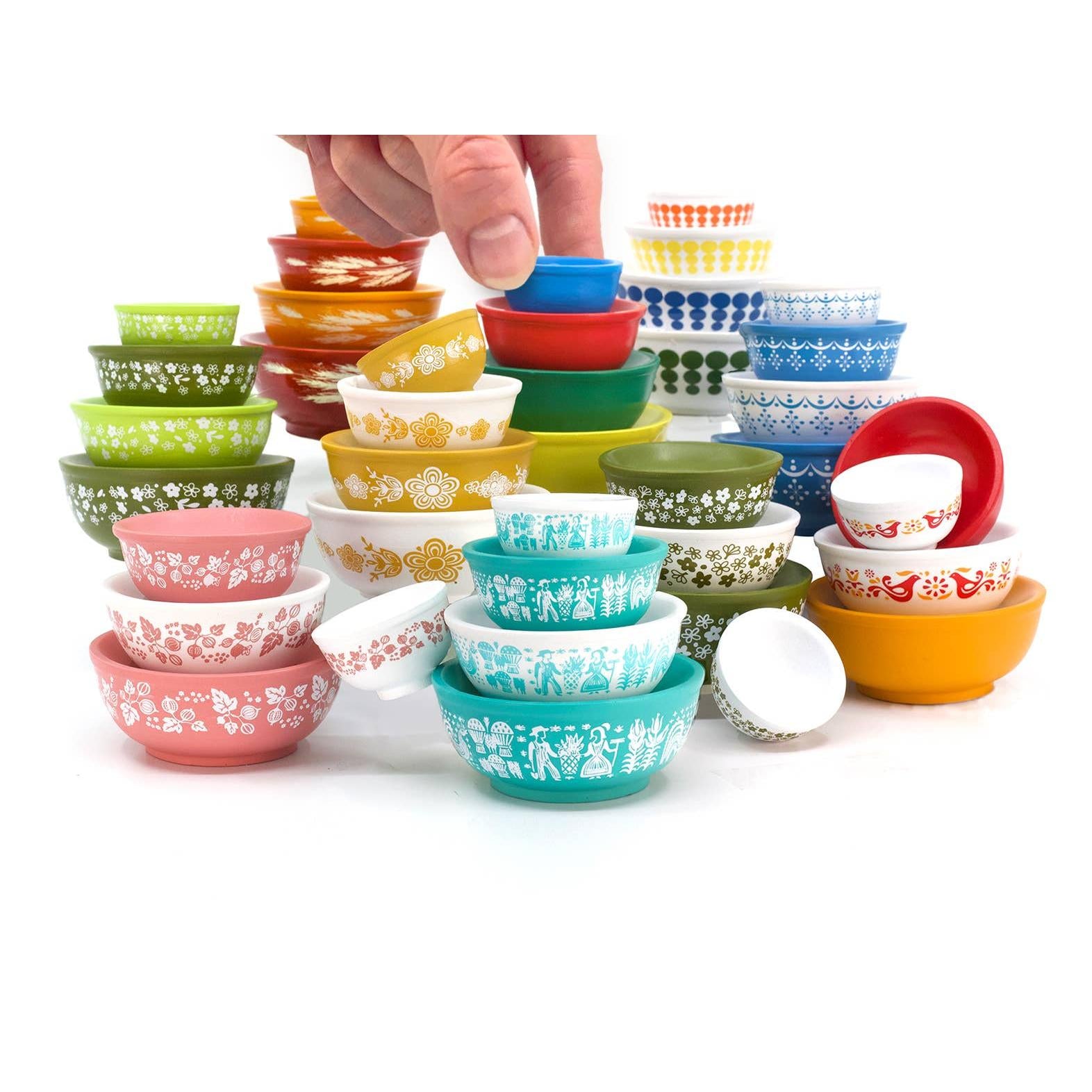 Colorful set of mini Pyrex-inspired patterned bowls stacked and arranged on a white background