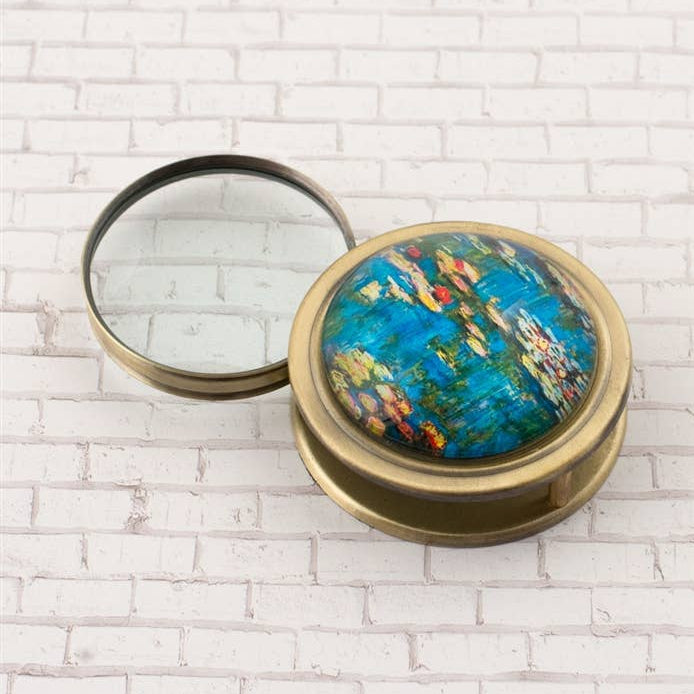 Compact magnifying glass with artistic design on a white brick background