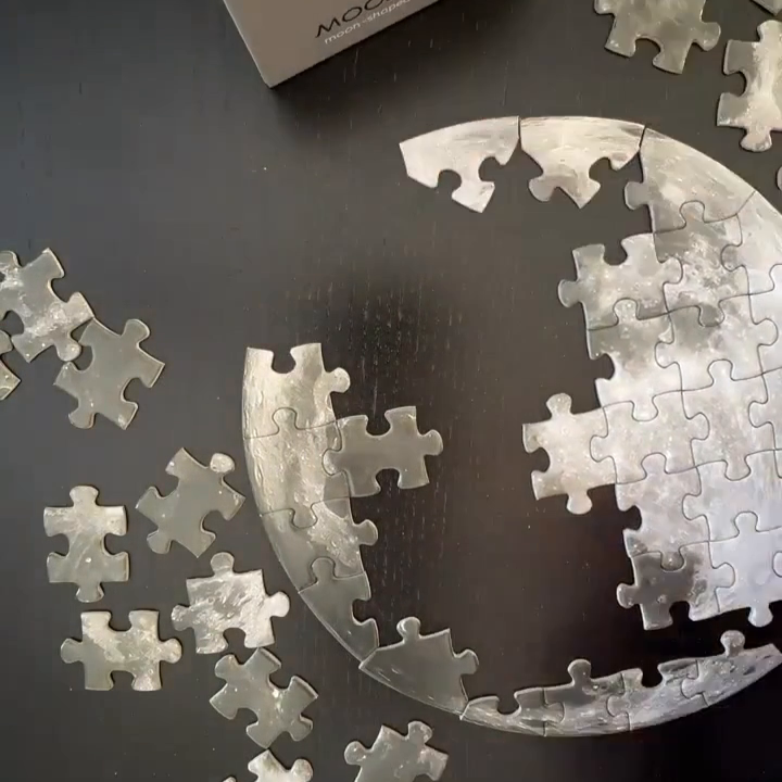 Moon-themed puzzle with pieces scattered on a dark surface, featuring the brand 'Moon Magic'.