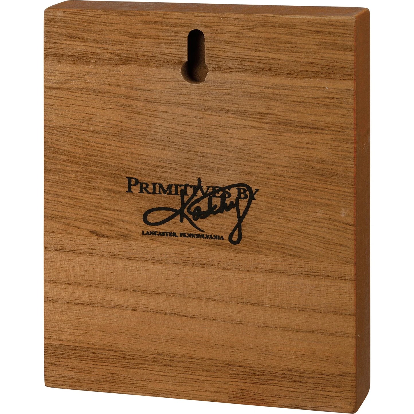 Wooden block with 'Primitives by Kathy' logo on a white background