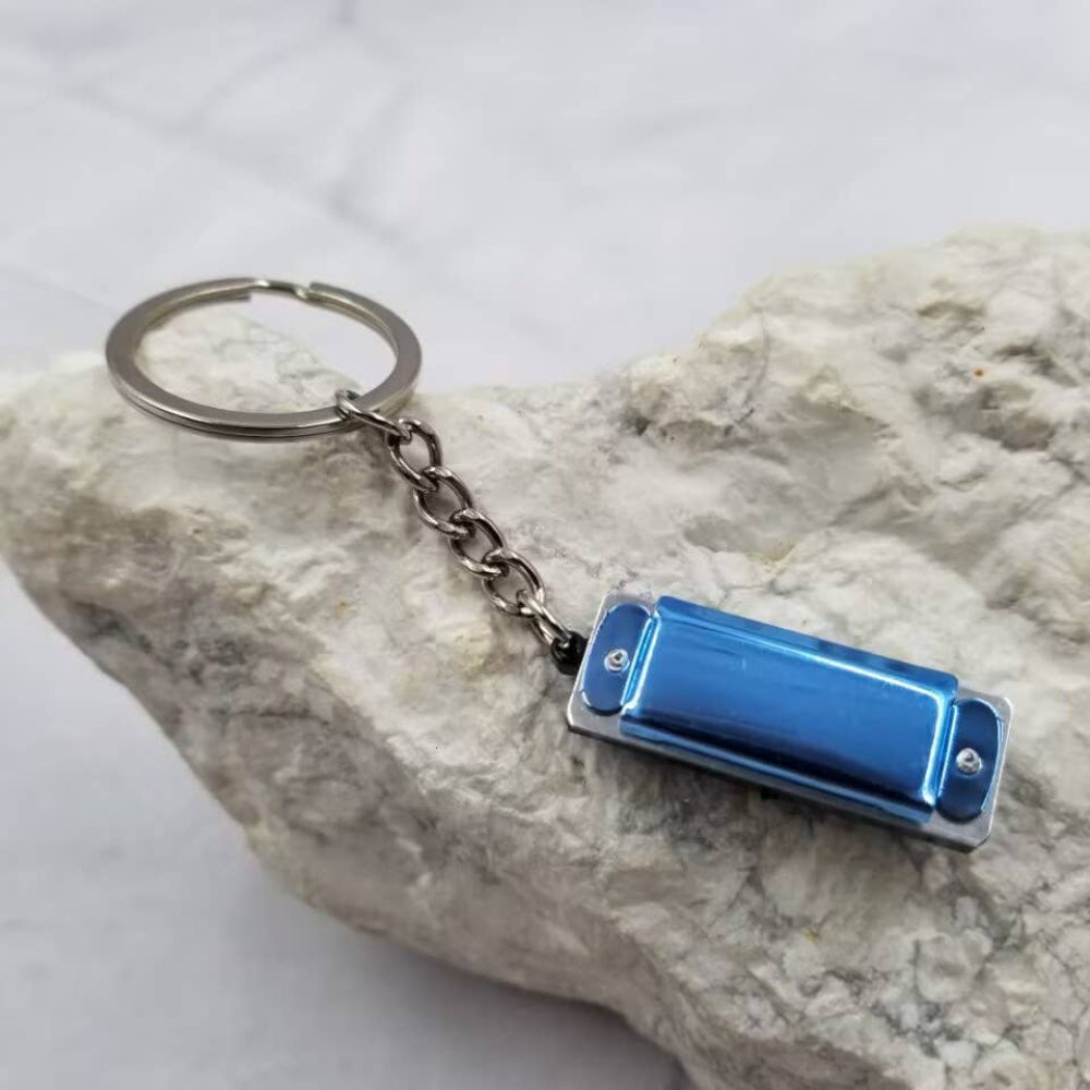 Blue harmonica-shaped keychain on a rock