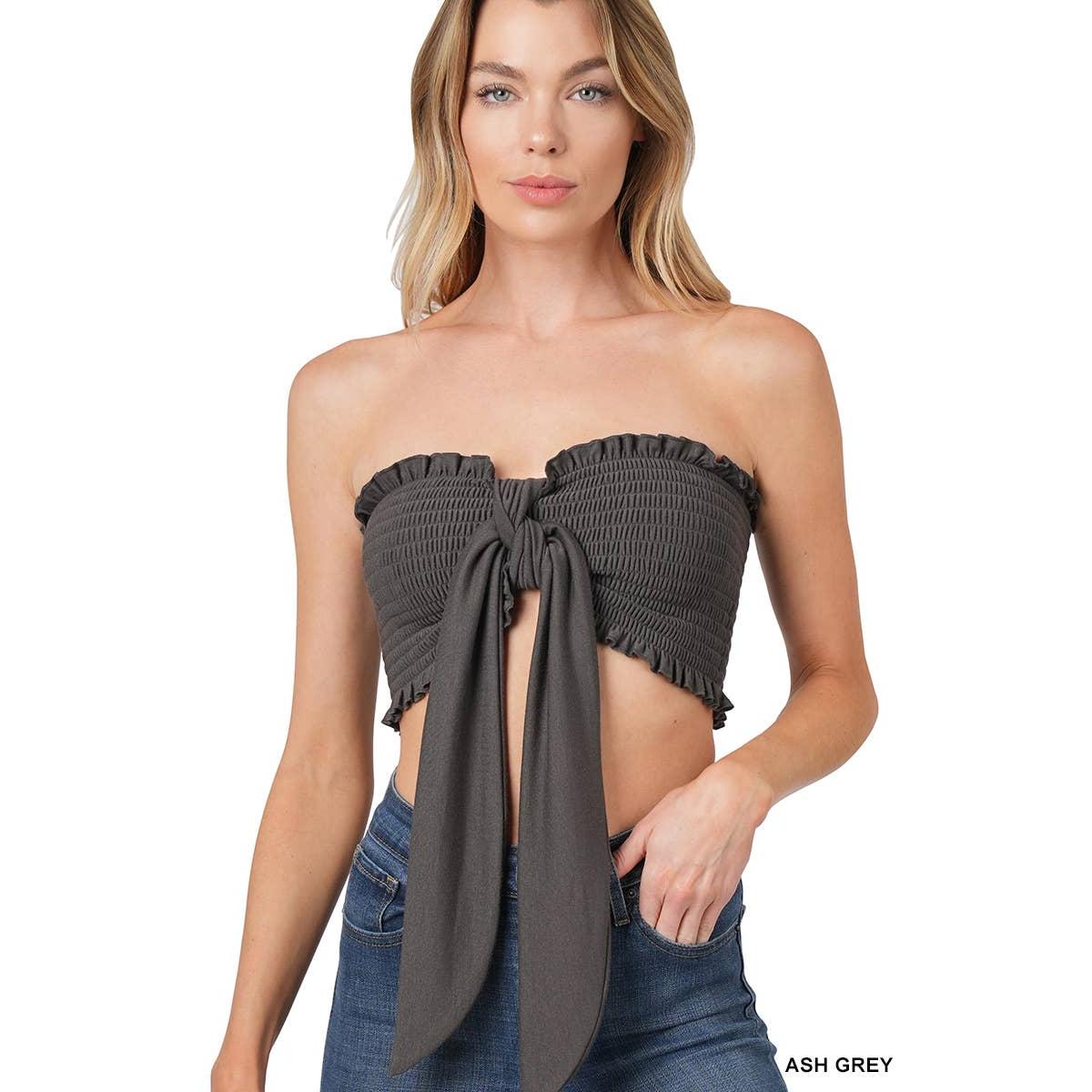 Woman wearing an ash grey strapless top with a tie detail on a white background