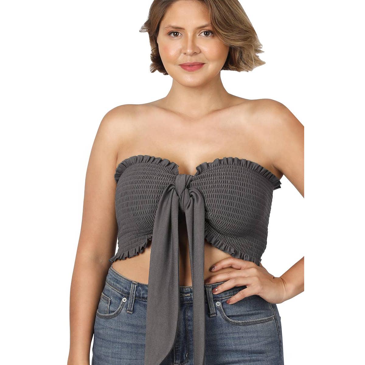 Woman wearing a gray strapless top with a tie detail and blue jeans on a white background