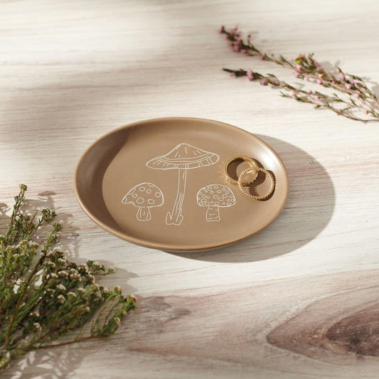 Brown ceramic plate with mushroom designs on a wooden surface with decorative branches.
