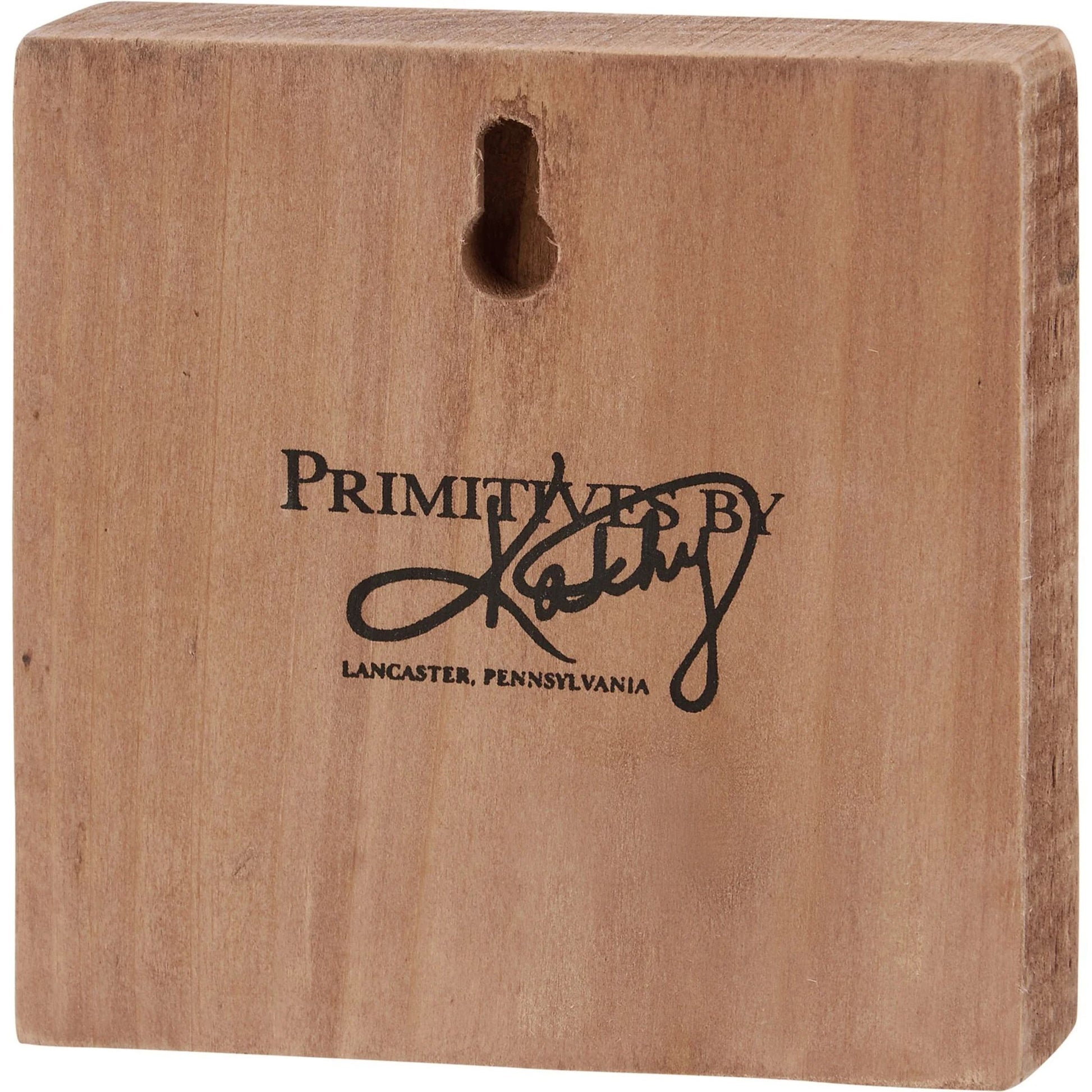 Wooden block with 'Primitives by Kathy' logo and text
