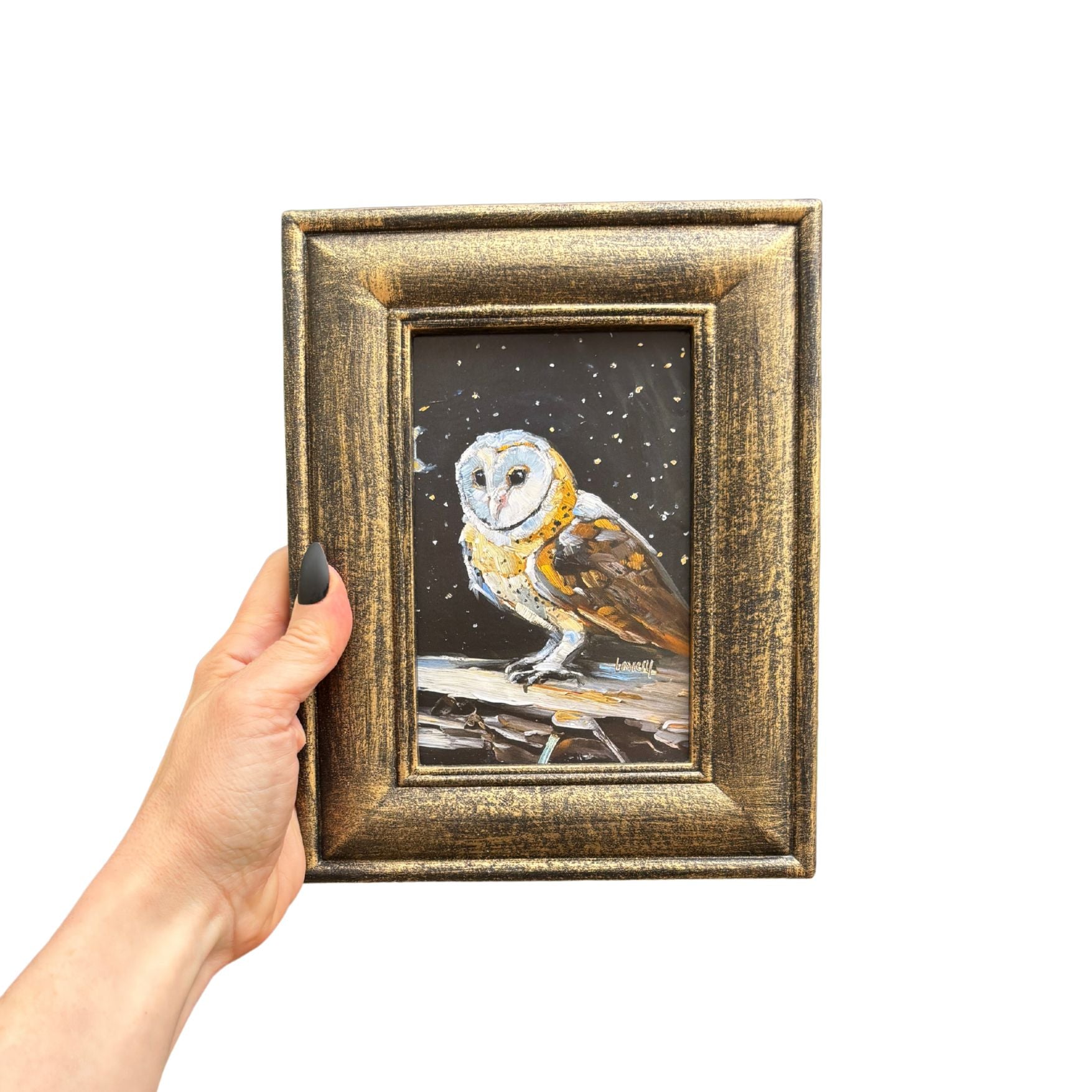 Framed artwork of an owl held by a hand on a white background