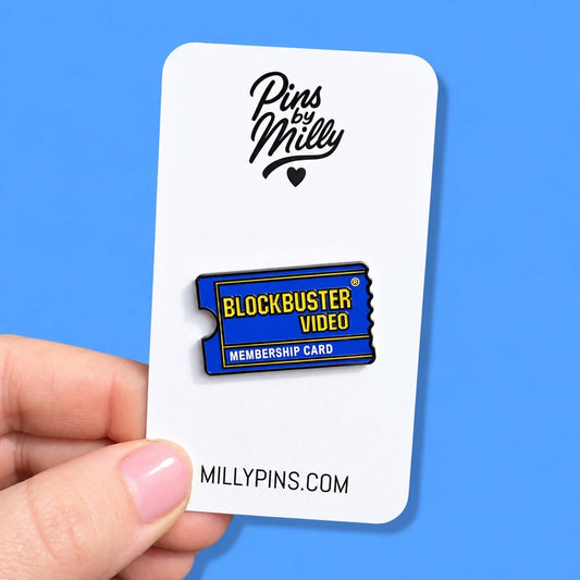 Featuring an enamel pin shaped like a movie ticket. The pin is blue with yellow and white text reading 'BLOCKBUSTER VIDEO' and 'MEMBERSHIP CARD.
