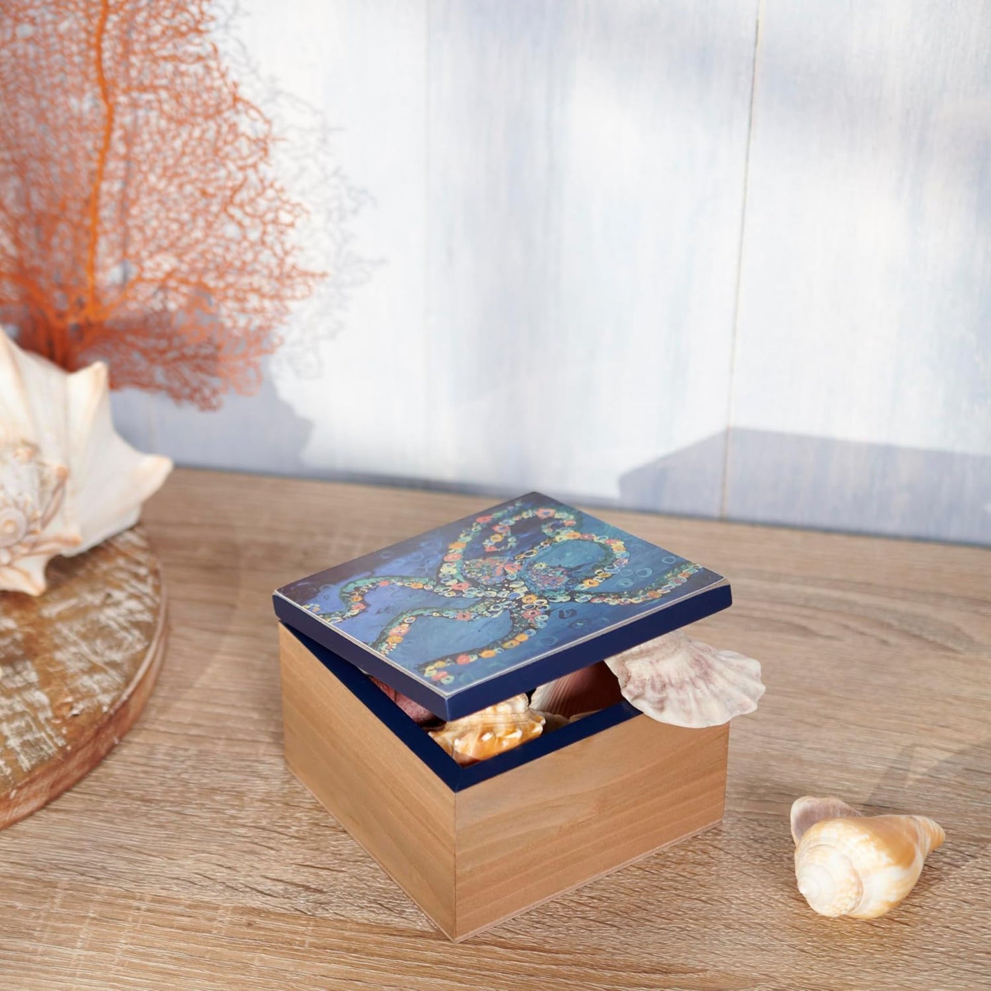 Wooden box with a blue lid featuring an octopus pattern on a wooden surface with seashells.