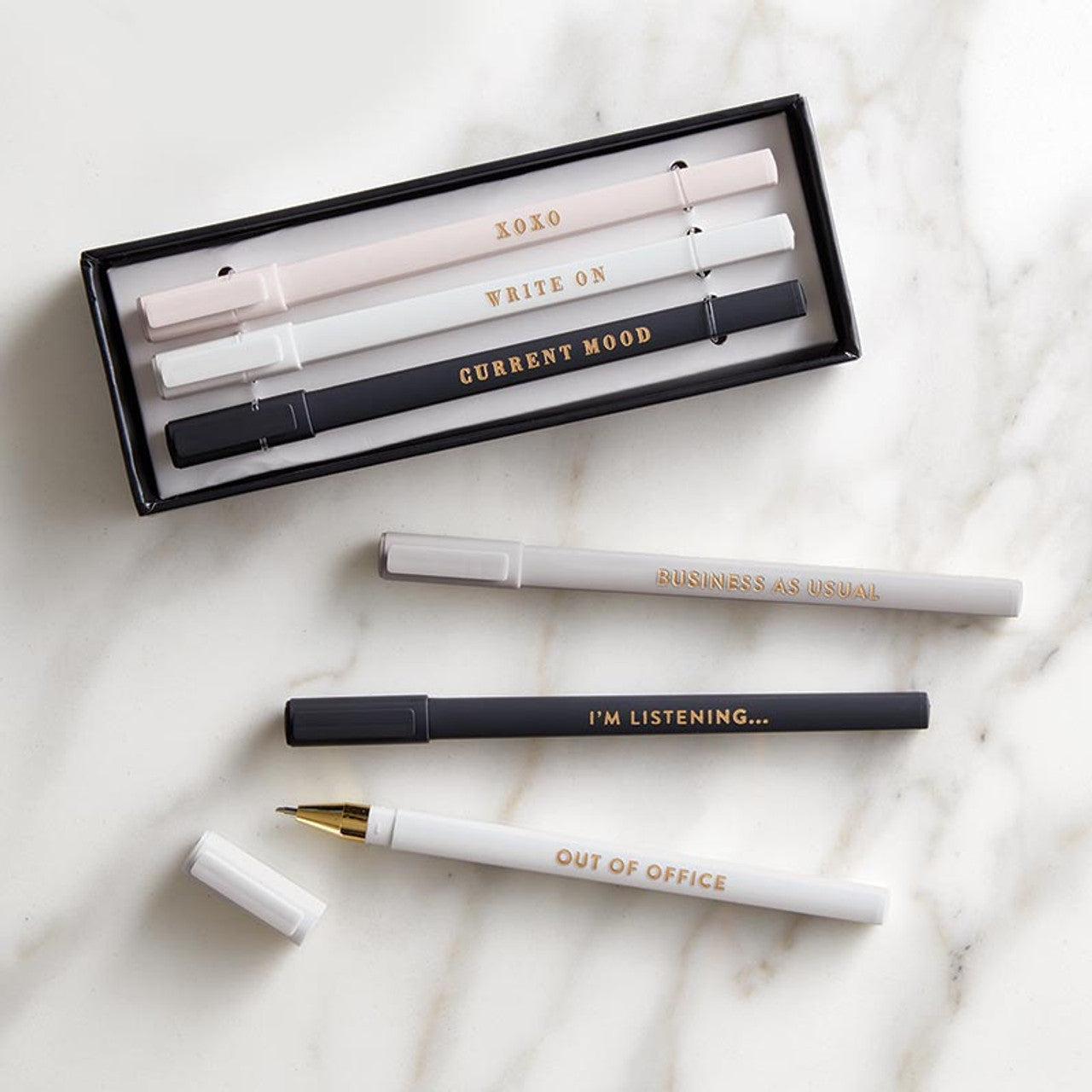 Set of pens with gold text on a marble surface