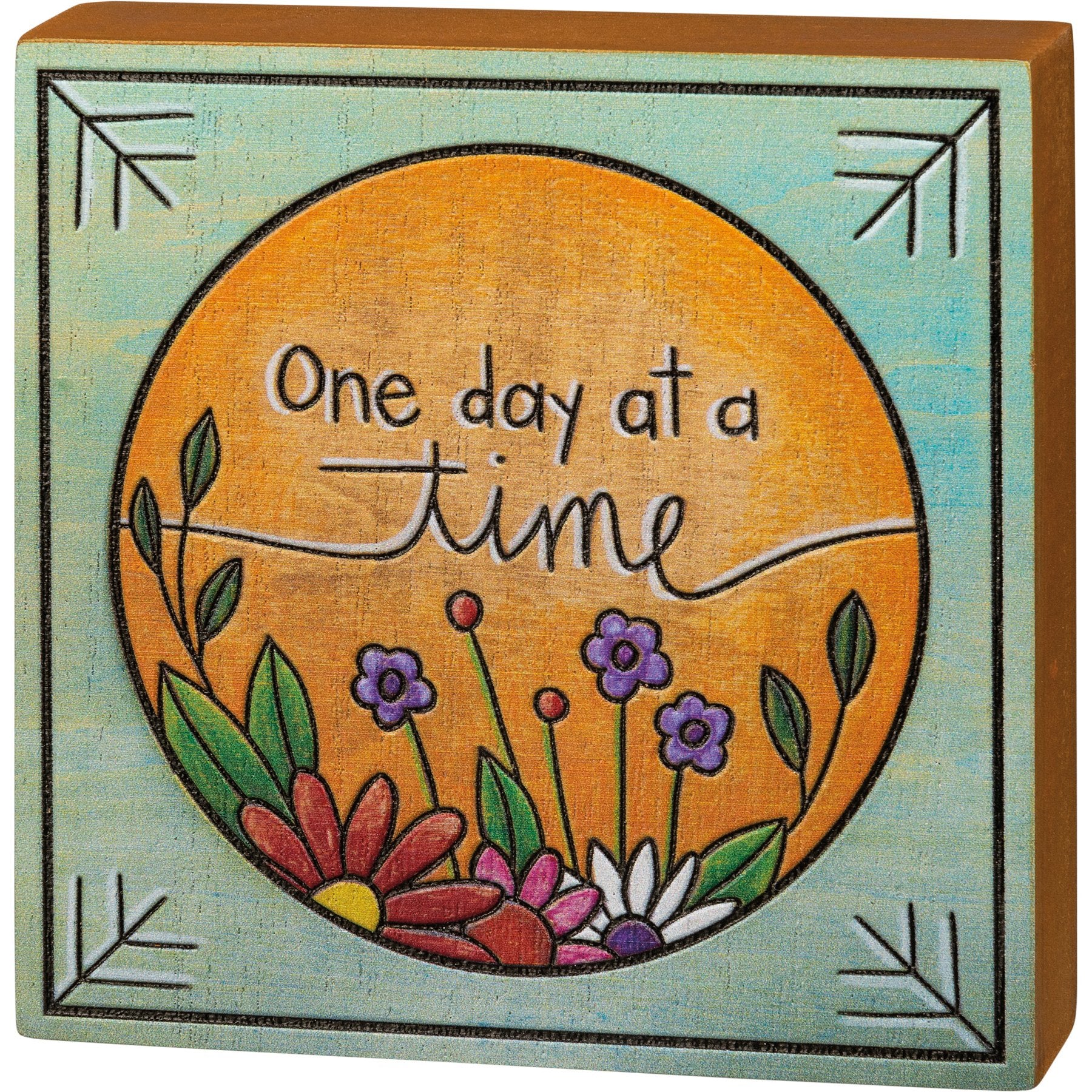 Decorative wooden block with 'One day at a time' text and floral design on a teal background