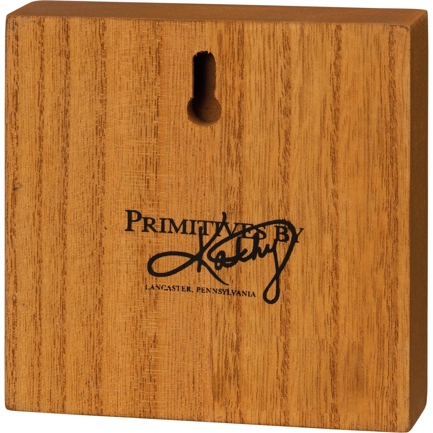 Wooden block with 'Primitives by Kathy' logo on a white background